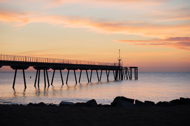 Nascer do sol no mar mediterrâneo com vista do pontão e da praia pont del petroli badalona barcelona catalunha espanha