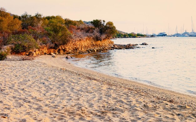 Nascer do sol ou pôr do sol na praia em Porto Rotondo, na Costa Smeralda, no mar Mediterrâneo, na ilha da Sardenha, na Itália. Barco na Sardenha no verão.