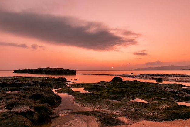 Nascer do sol pacífico em poças de água do mar à beira-mar entre rochas costeiras colorido céu rosa
