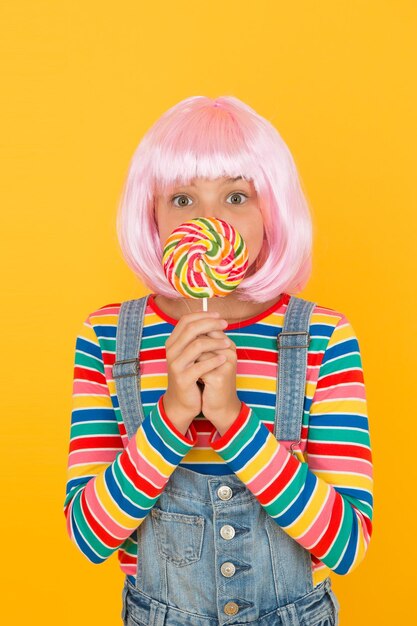 Naschkatzen Kleines Kind halten Lutscher Süßigkeiten gelben Hintergrund Kleines Mädchen mit Regenbogenstrudel Süßigkeiten auf Stick Entzückendes Kind genießen Kandiszucker Dessert Bester Süßwarenladen