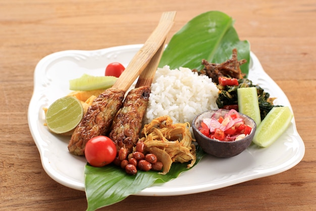 Nasi Campur Bali. Refeição popular balinesa de arroz com vários acompanhamentos, servidos juntos. Este menu contém Ayam Sisit, Sate Lilit, Refogue folha de mamão e Sambal Matah.