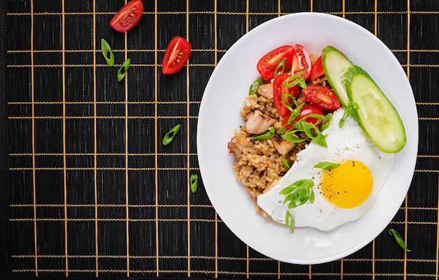 Nasi Goreng. Arroz frito de frango indonésio em fundo escuro. Nasi Goreng é um prato da culinária indonésia com arroz, carne de frango, cebola, ovo, vegetais. Vista superior, acima, copie o espaço