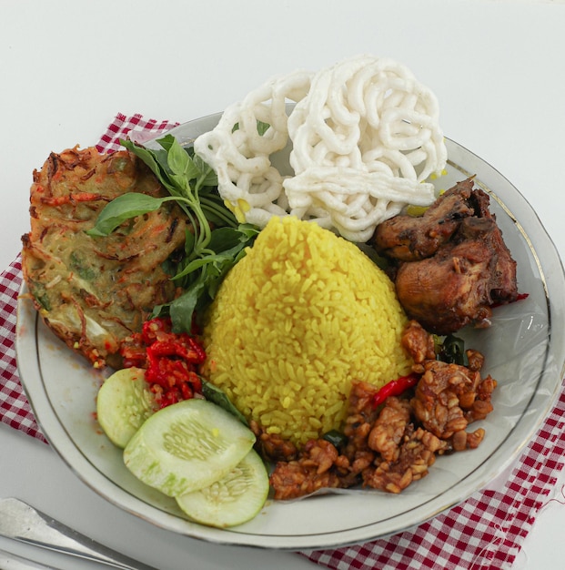 Nasi kuning o arroz amarillo en forma de cono, presentación de plato de arroz festivo indonesio con un poco de condimento