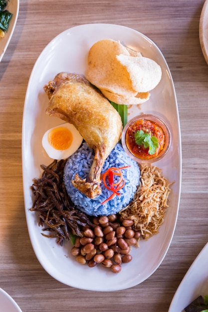 Nasi lemak ist ein malaiischer reis, der in kokosmilch gekocht und mit gebratenem huhn serviert wird.