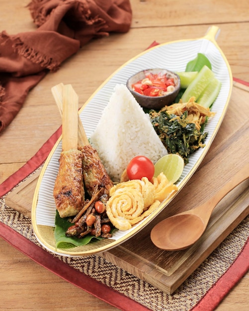 Nasi Lemak ou Nasi Campur Bali Arroz Balinês indonésio com Sate Lilit Ayam Sisit Sambal Matah e amendoim