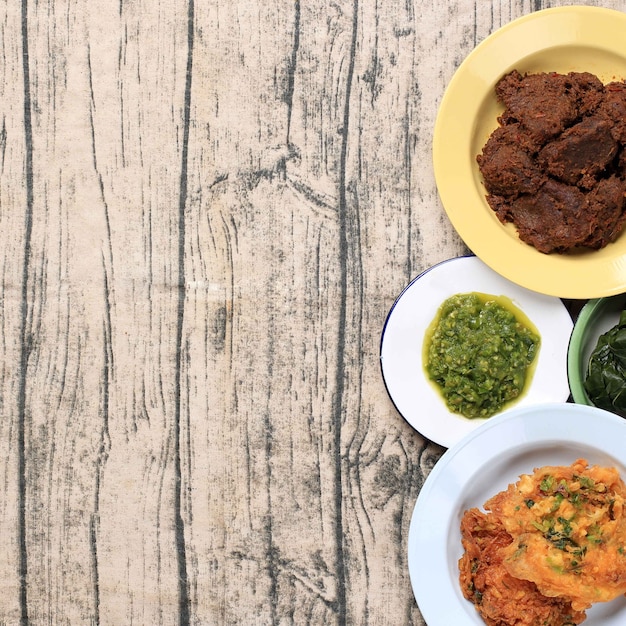 Foto nasi padang indonesia food, rendang, egg y lado mudo. copie el espacio sobre fondo de madera