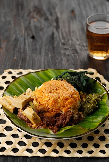 Nasi Padang servido con Rendang Young Jackfruit Curry Hojas de mandioca y Sambal Hijau o Lado Mudo en mesa de madera