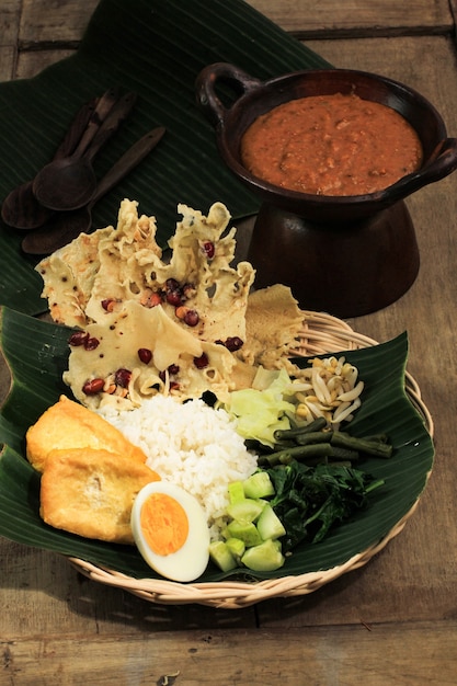 Nasi Pecel. Plato de arroz tradicional javanés de arroz al vapor con ensalada de verduras, aderezo de salsa de maní, tempeh, tofu y galletas Peyek. Pecel Madiun es la variante más popular