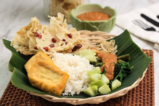 Nasi Pecel. Prato de arroz javanês tradicional de arroz cozido no vapor com salada de vegetais, molho de molho de amendoim, tempeh, tofu de tofu e bolachas de Peyek. Pecel Madiun é a variante mais popular