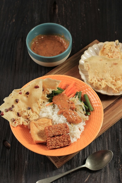 Nasi Pecel. Prato de arroz javanês tradicional de arroz cozido no vapor com salada de vegetais, molho de molho de amendoim, tempeh, tofu de tofu e bolachas de Peyek. Pecel Madiun é a variante mais popular