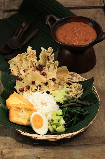 Nasi Pecel. Prato de arroz javanês tradicional de arroz no vapor com salada de vegetais, molho de molho de amendoim, tempeh, tofu de tofu e bolachas de Peyek. Pecel Madiun é a variante mais popular