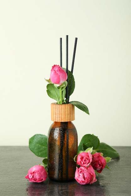 Nasse Diffusorflasche mit Stäbchen und rosa Rosen