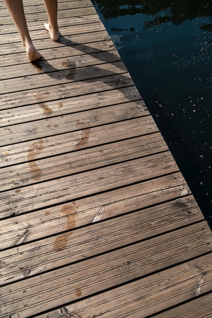 Nasse Fußspuren, die von Frauenfüßen auf einem Holzsteg hinterlassen wurden Schwimmen im See