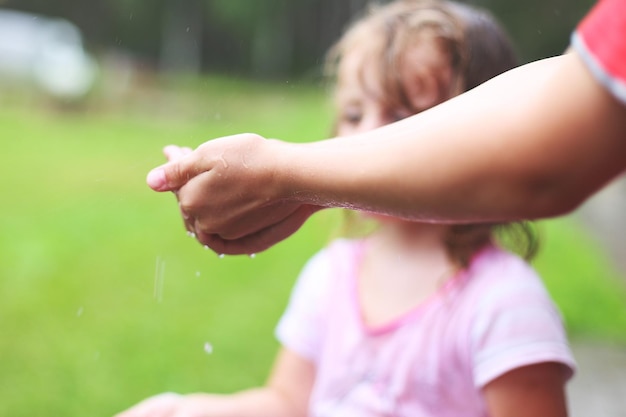 Nasse Hände schließen Jungen und Mädchen spielen im regnerischen Sommerpark Bruder und Schwester spielen bei regnerischem Wetter