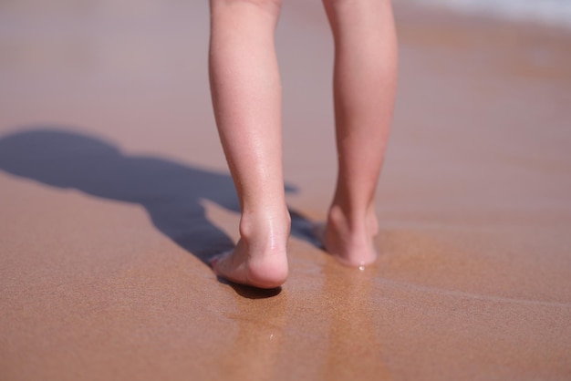 Nasse nackte Füße gehen am Strand entlang in der Nähe des Meeres