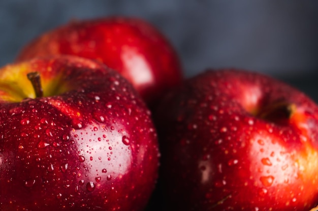 Nasse und saftige frische rote Äpfel mit Wassertropfen auf dunklem Hintergrund mit Nahansicht. Selektiver Fokus