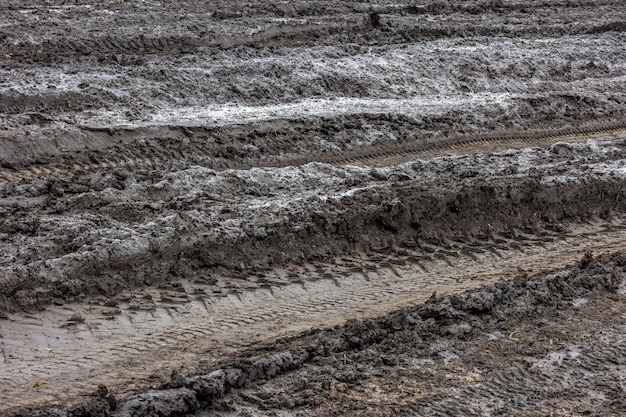 Nasser Schotterweg nach Regen Lehmschmutz und Erde bei bewölktem Tageslicht in der Herbstsaison