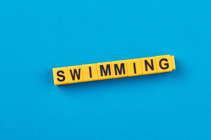 Foto natación de palabras escrita en cubos amarillos sobre fondo azul plano