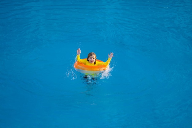 Natación vacaciones de verano niño nadar en la piscina en anillo inflable niño con anillo inflatable en la natación