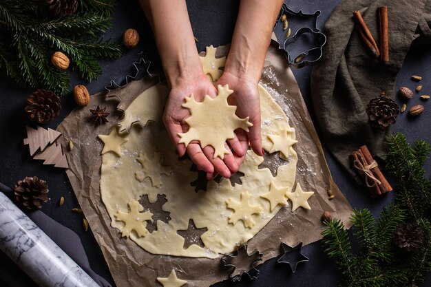 Natal assado em casa mãos femininas fazendo biscoitos de floco de neve de massa fresca vista de cima