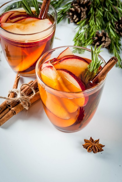 Natal, bebidas de ação de graças. outono, coquetel de inverno grogue, sangria quente, vinho quente - maçã, alecrim, canela, anis. na mesa de mármore branco. com cones, alecrim. copie o espaço