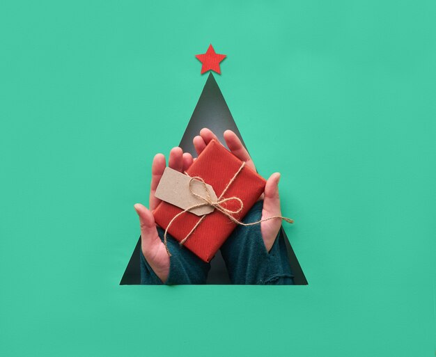 Foto natal criativo geométrico plano leigos nas cores verde e vermelho de biscaia. enfeites de natal no buraco do papel triangular em forma de árvore de natal com estrela de papel vermelho.