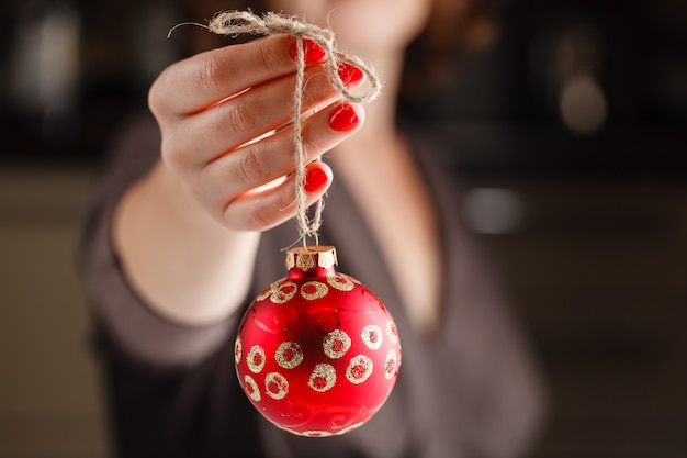 Natal, decoração, feriados e conceito dos povos - próximo acima da mão da mulher que guarda a bola vermelha do Natal