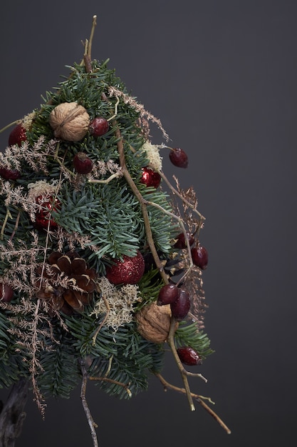 Natal e composição. Árvore de Natal feita de galhos de pinheiro e decorada com materiais naturais e bolas no escuro