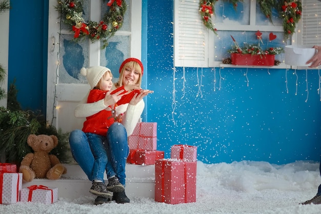 Natal em tempo de inverno, mãe e filha no fundo do cenário e caixas de Natal no estúdio fotográfico.