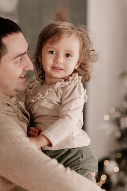 Natal. Família. Ame. jovem pai e filha perto da árvore de Natal em casa.