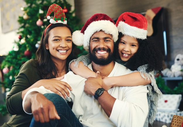 Natal feliz e retrato de família na sala de estar para celebração de afeto e sorriso festivo de férias e união com a menina abraçam os pais em casa pelo conteúdo gratidão e férias de natal