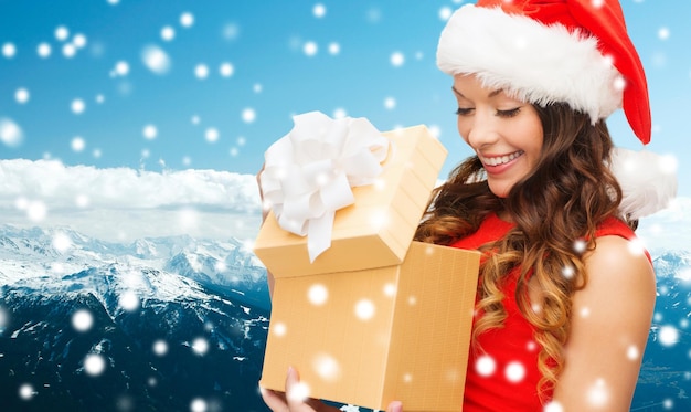 natal, feriados, celebração e conceito de pessoas - mulher sorridente de vestido vermelho com caixa de presente sobre fundo azul nevado