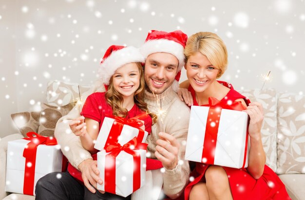 natal, feriados, família e conceito de pessoas - feliz mãe, pai e filha em chapéus de ajudante de papai noel com caixas de presente e estrelinhas