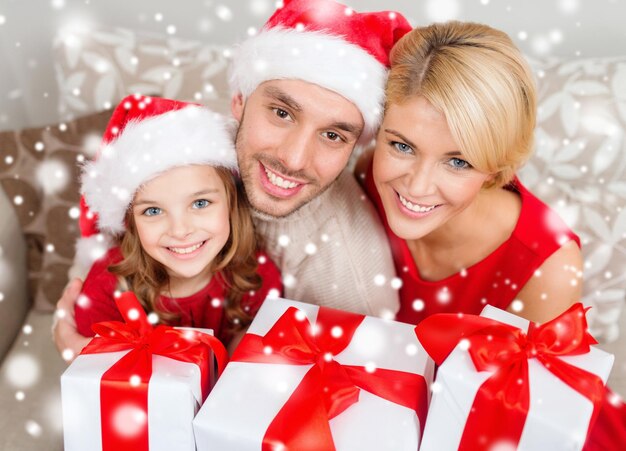 natal, feriados, felicidade e conceito de pessoas - família sorridente em chapéus de ajudante de papai noel com muitas caixas de presente em casa