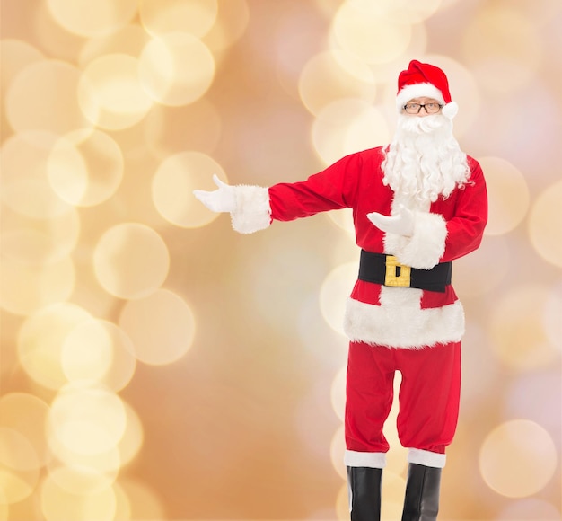 natal, feriados, gesto e conceito de pessoas - homem fantasiado de papai noel sobre fundo de luzes bege