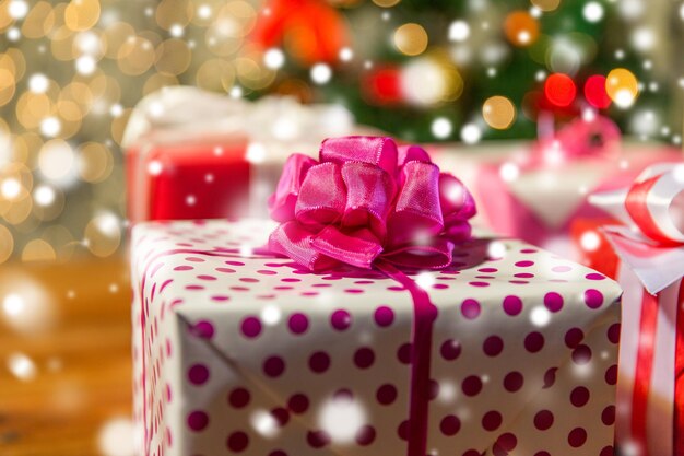 natal, feriados, presentes, ano novo e conceito de celebração - close-up de caixas de presente sobre as luzes da árvore de natal