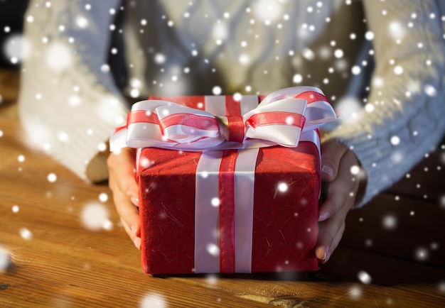 natal, feriados, presentes, ano novo e conceito de pessoas - close-up de mãos de mulher segurando uma caixa de presente decorada com laço