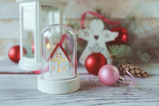 Natal, lanterna branca com uma vela acesa, anjos de brinquedo, sobre fundo de madeira