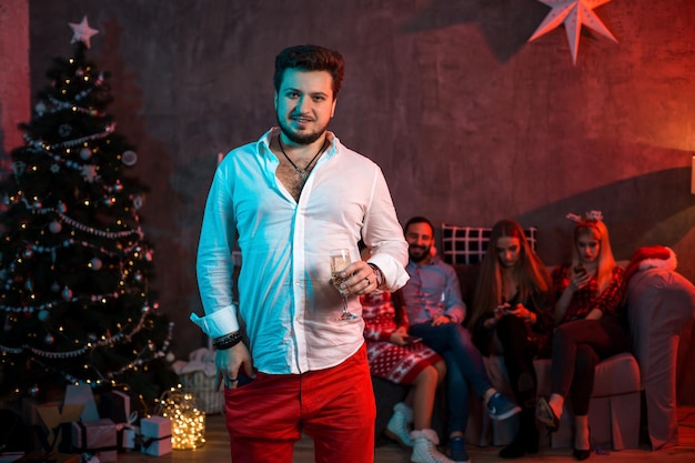 Natal, Natal, ano novo, inverno, conceito de felicidade - homem sorridente com uma taça de champanhe. Pessoas engraçadas. Festa de natal em casa