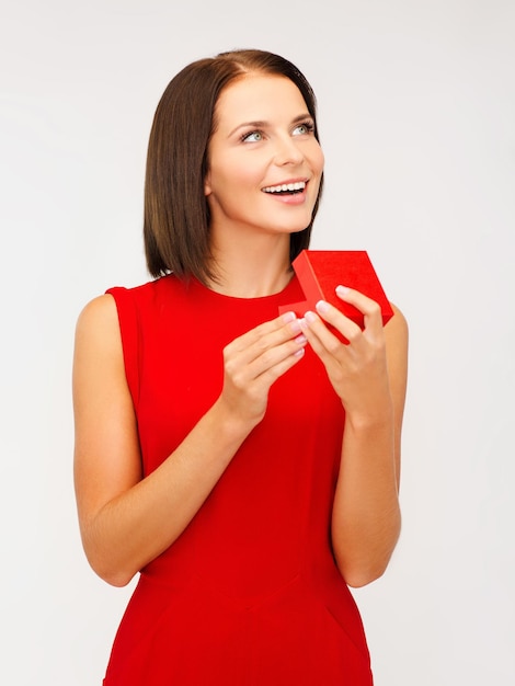 Foto natal, natal, dia dos namorados, conceito de celebração - mulher surpresa em um vestido vermelho com caixa de joias