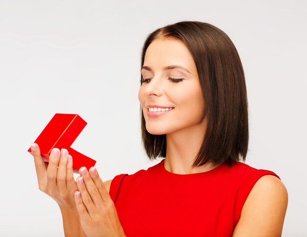 natal, natal, dia dos namorados, conceito de celebração - mulher surpresa em um vestido vermelho com caixa de joias