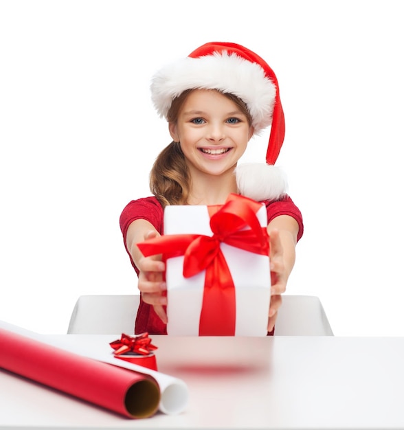 natal, natal, inverno, conceito de felicidade - menina sorridente com chapéu de ajudante de Papai Noel com caixa de presente