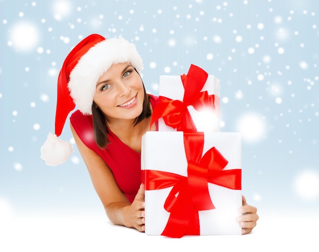 natal, natal, inverno, conceito de felicidade - mulher sorridente com chapéu de ajudante de Papai Noel com muitas caixas de presente