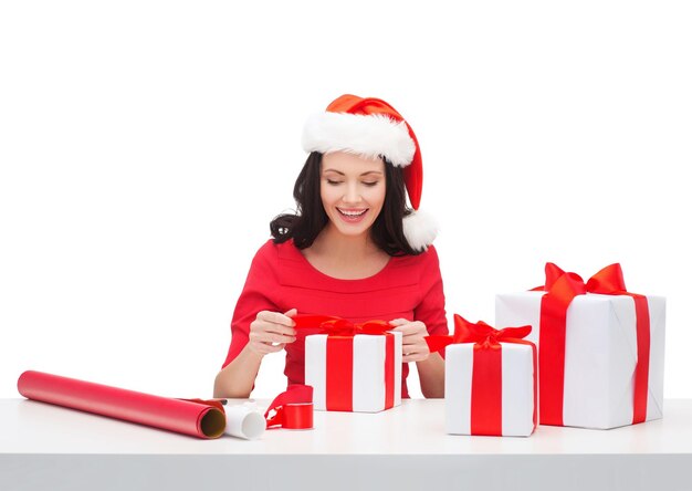 natal, natal, inverno, conceito de felicidade - mulher sorridente com chapéu de ajudante de Papai Noel com muitas caixas de presente