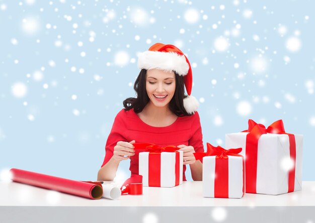 natal, natal, inverno, conceito de felicidade - mulher sorridente com chapéu de ajudante de Papai Noel com muitas caixas de presente