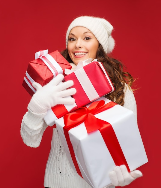 natal, natal, inverno, conceito de felicidade - mulher sorridente com suéter e chapéu com muitas caixas de presente