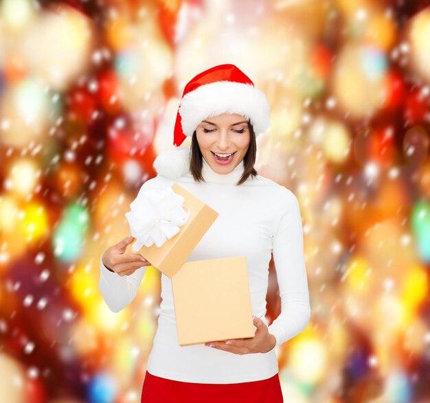 natal, natal, inverno, conceito de felicidade - mulher surpresa com chapéu de ajudante de Papai Noel com caixa de presente