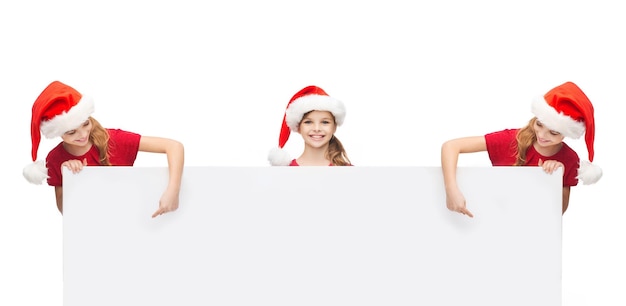 natal, natal, pessoas, propaganda, conceito de venda - meninas com chapéus de ajudante de Papai Noel com quadro branco em branco