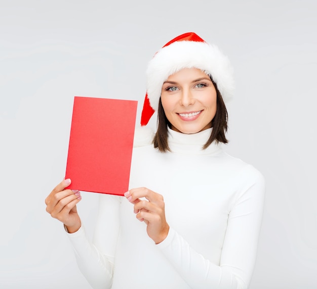 natal, natal, pessoas, propaganda, conceito de venda - mulher feliz com chapéu de ajudante de Papai Noel com cartão vermelho em branco