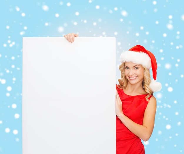 natal, natal, pessoas, propaganda, conceito de venda - mulher feliz com chapéu de ajudante de Papai Noel com quadro branco em branco